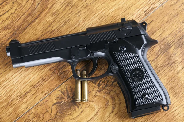 Handfeuerwaffe und Messingkugeln auf Holzgrund — Stockfoto
