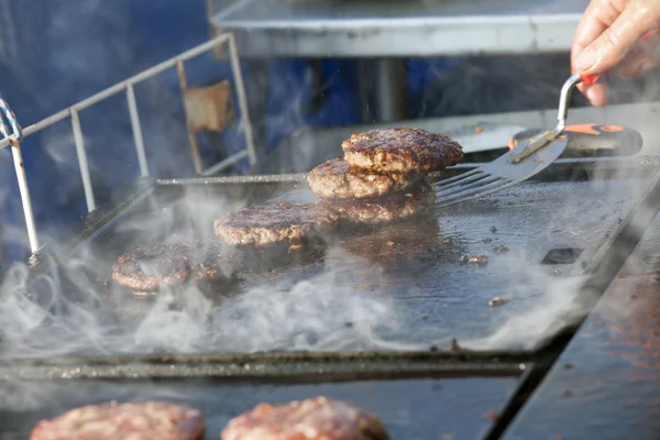 Burgers essere cucinati su una cucina a gas all'aperto Foto Stock