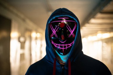 Karanlıkta neon maskeli bir suçlu. Seçici odak