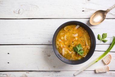 Lezzetli tavuk suyu çorbası, kaşık ve beyaz arka planda baharatlı otlar.