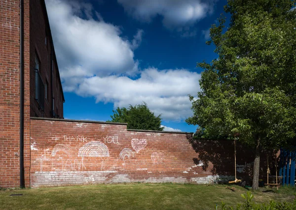 Bahar 2020 'de İngiltere' deki Covid salgını sırasında NHS 'ye teşekkür eden bir bahçe duvarında tebeşir gökkuşağı ve yazı vardı.