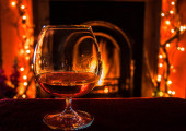 Sklenice ohřívání brandy u útulného krbu v zimě.