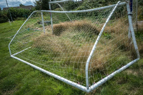 Abandoned football goal posts in a field.