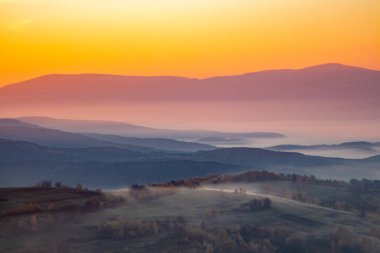 Şafakta dağlarda sisli tepeler arasında.