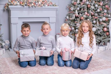 İki erkek ve iki kız noel hediyelerini Noel dekoru ile birlikte odada tutuyorlar..
