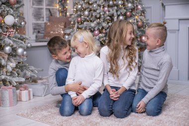 İki erkek ve iki kız Noel dekoruyla odada kucaklaşıyorlar. Birbirinizi sevin.