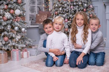 İki erkek ve iki kız Noel dekoruyla odada kucaklaşıyorlar. Birbirinizi sevin.