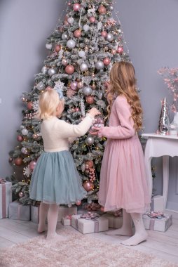 İki kız Noel günü odada bir Noel ağacı süslüyor..