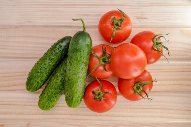 Ahşap masa manzaralı kırmızı domates ve yeşil salatalıklar..