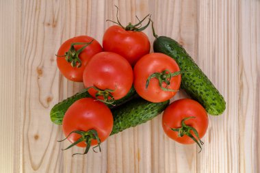 Ahşap masa manzaralı kırmızı domates ve yeşil salatalıklar..