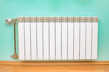 Yeşil duvarlı bir odada beyaz radyatörler. ev ısıtma tipi.