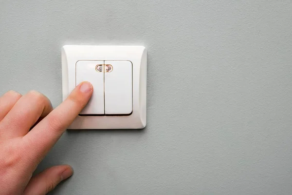 the boy turns off the light on the switch on the wall in the room. Electricity consumption.