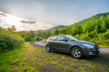 WILSHINTSI, UKRAINE - 10 Haziran 2020: Hyundai ve 30 hatchback arabası sisli dağlarda bir kır yolunda. Yazın gün doğumunda güzel bir nakliye manzarası. araba konseptiyle seyahat.