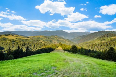 Buzullar, sabah güneşinin ılık bir sonbahar gününde parladığı dağların arka planında çimlerle kaplıdır. Toprak ekolojisi kavramı. Mavi gökyüzü ve beyaz bulutlar. güzel doğa. 