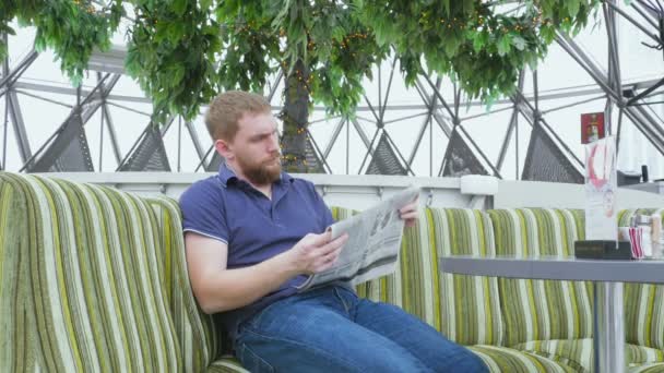 Νέοι γενειοφόρος άνδρας διαβάζει την πρωινή εφημερίδα — Αρχείο Βίντεο