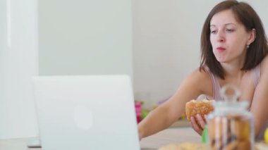 Kadın hamburger yiyor ve laptop ile çalışır