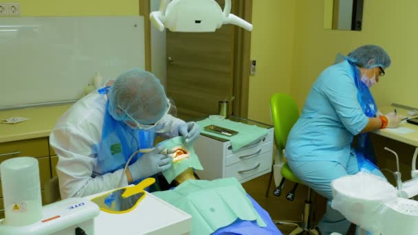 Стоматолог очищает зубы пациентки специальным оборудованием — стоковое видео