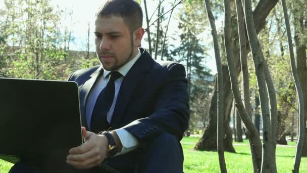 Businessman works with laptop in the city park — Stock Video