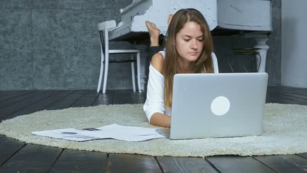 Fiatal barna feküdt a szőnyegen, és használ laptop — Stock videók