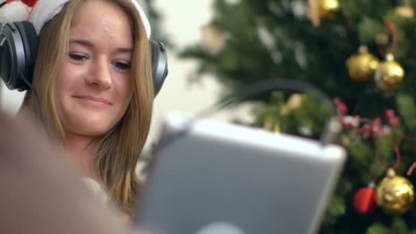 Sonriente chica en brillante usando almohadilla contra el árbol de Navidad — Vídeos de Stock