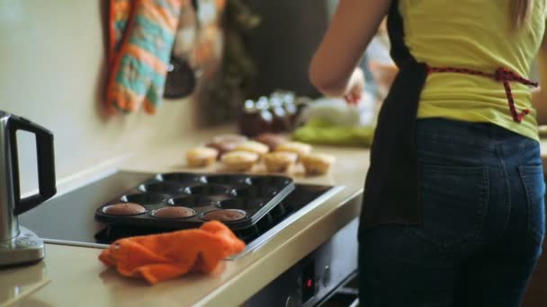 Cocinera saca magdalenas recién horneadas de la bandeja — Vídeo de stock