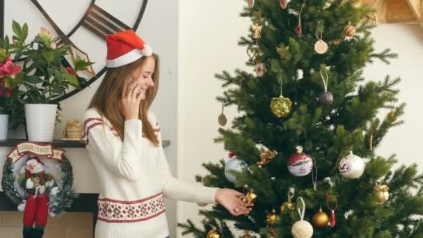 Hezká dívka mluví po telefonu okolí vánoční stromeček — Stock video
