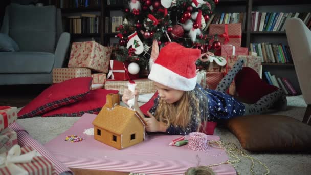 Kleines Mädchen schmückt Lebkuchenhaus — Stockvideo