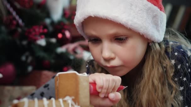 Mädchen schmückt Lebkuchenhaus — Stockvideo
