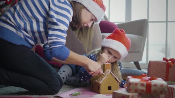 Mother with daughter decorates gingerbread house — Stock Video