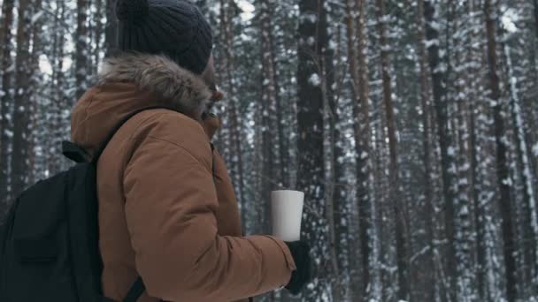 Muž s termoskou v zimním lese — Stock video