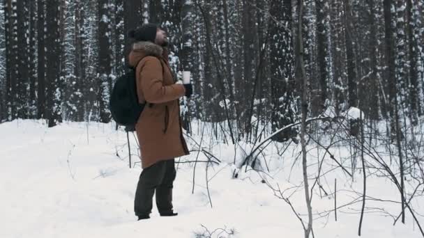 Muž s termoskou v zimním lese — Stock video