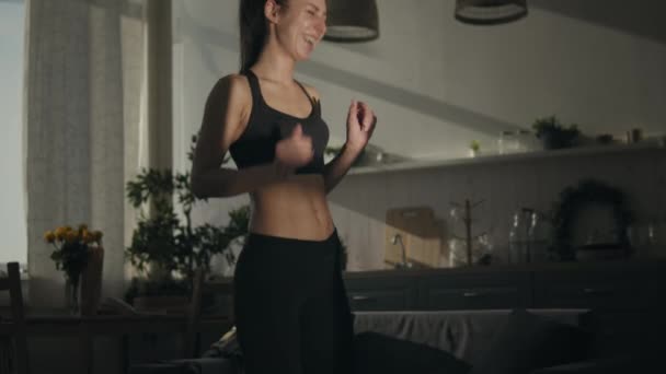 Vrouw dansend naar muziek thuis in zonlicht — Stockvideo