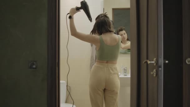 Chica seca el cabello con secador de pelo en el baño. — Vídeos de Stock