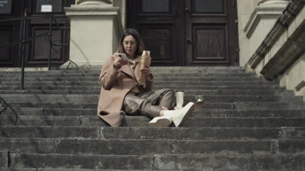 Joven mujer elegante comer comida rápida al aire libre — Vídeos de Stock