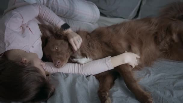 Ragazza con il suo cane coccole sul letto — Video Stock