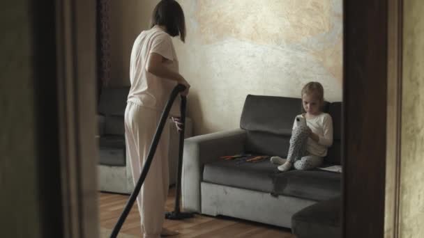 Жінка прибирає вітальню з пилососом — стокове відео