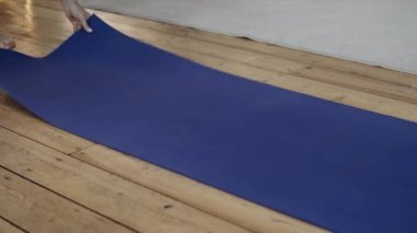 Yoga antremanından önce hasırı açan kadın