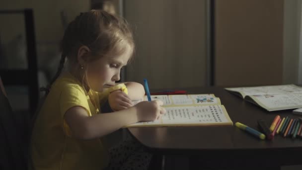 Дошкольная девочка делает домашнее задание дома — стоковое видео