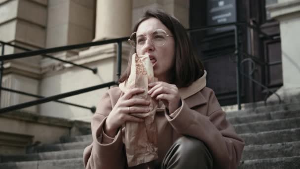 Stijlvol meisje eten fast food buiten — Stockvideo