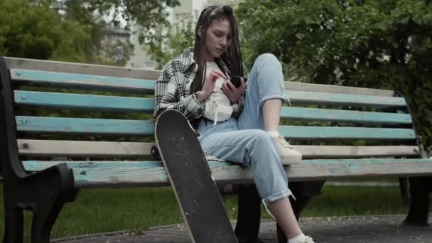Cool skater girl texting outdoors. — Stock Video