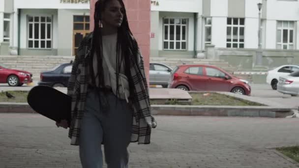 Fiatal női gördeszkás sétál a szabadban — Stock videók