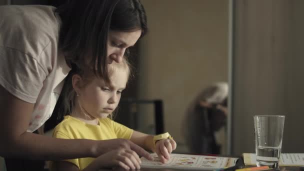 Petite fille faisant ses devoirs avec sa mère à la maison — Video