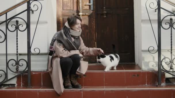Jonge vrouw aaien dakloze kat — Stockvideo