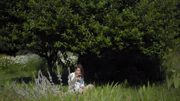 Una mujer bajo un árbol usando su teléfono — Vídeo de stock