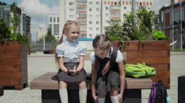 Okul bahçesinde konuşan iki küçük kız.