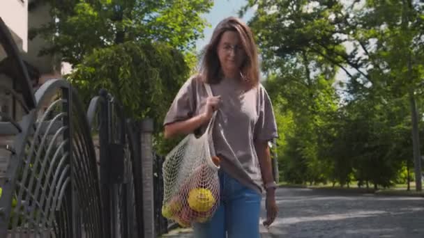 Femme portant des produits alimentaires dans un sac à ficelle réutilisable — Video
