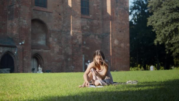 古代の建物の近くで本を読んでいる女性 — ストック動画