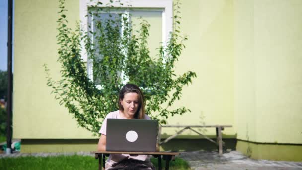 Kobieta pracuje z laptopem na podwórku — Wideo stockowe