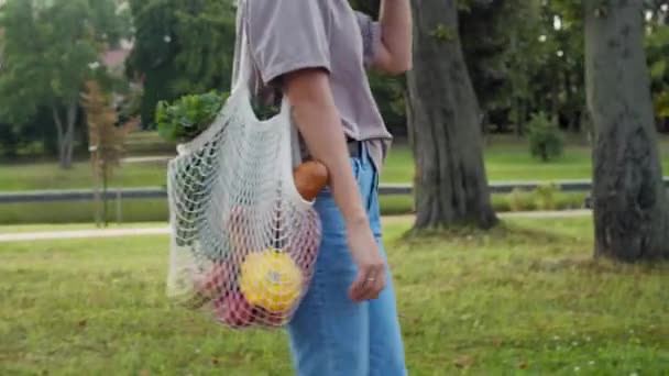 Mujer camina fuera con malla de hilo de punto bolsa de compras — Vídeo de stock