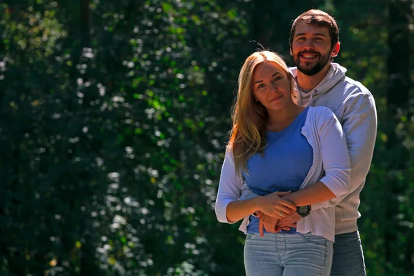 Young couple walks on sidewalk in forest — Stock Photo, Image